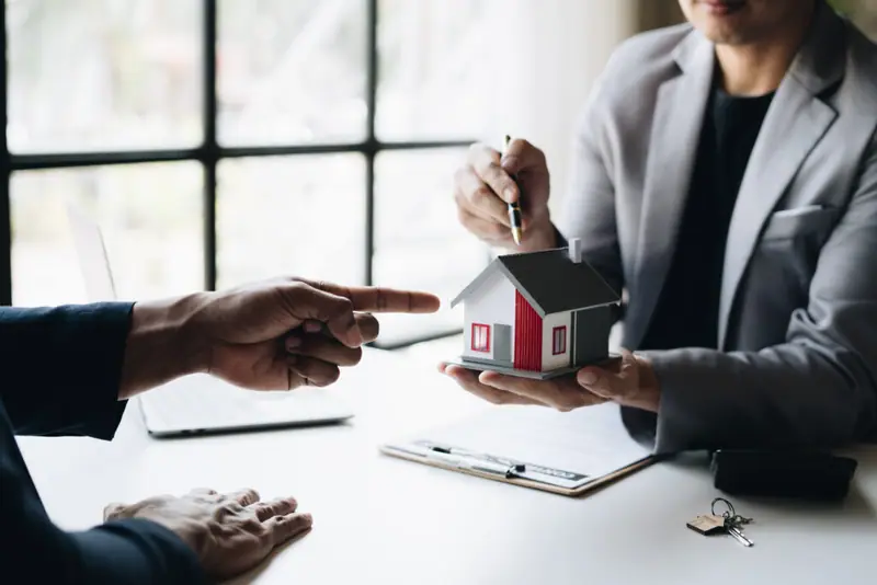 Berater überreicht Modellhaus an Kunden zur Immobilienbewertung